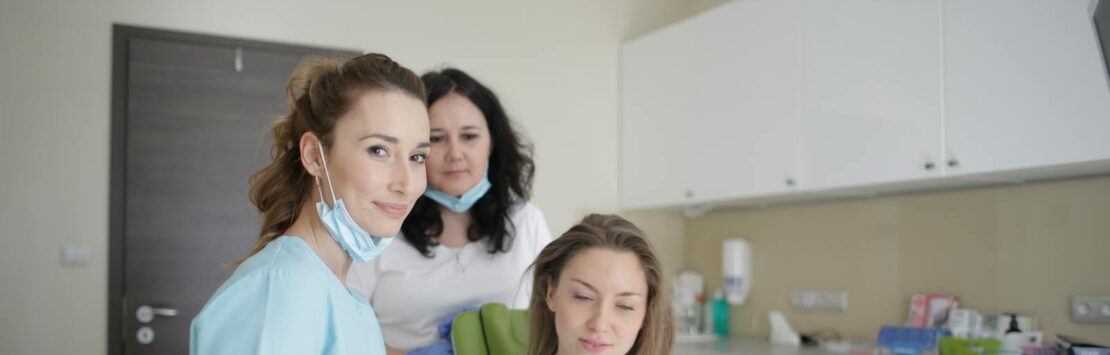 Photo by Andrea Piacquadio Dentists and patient engaging over a tablet in a clean, modern dental clinic.